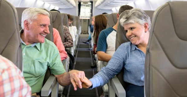 זוג בכיר מחזיק ידיים בזמן על מטוס